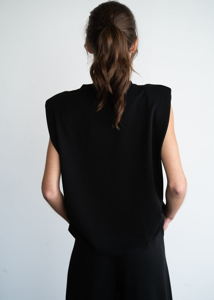 Black sleeveless top with structured shoulder pads, shown from back view on model.