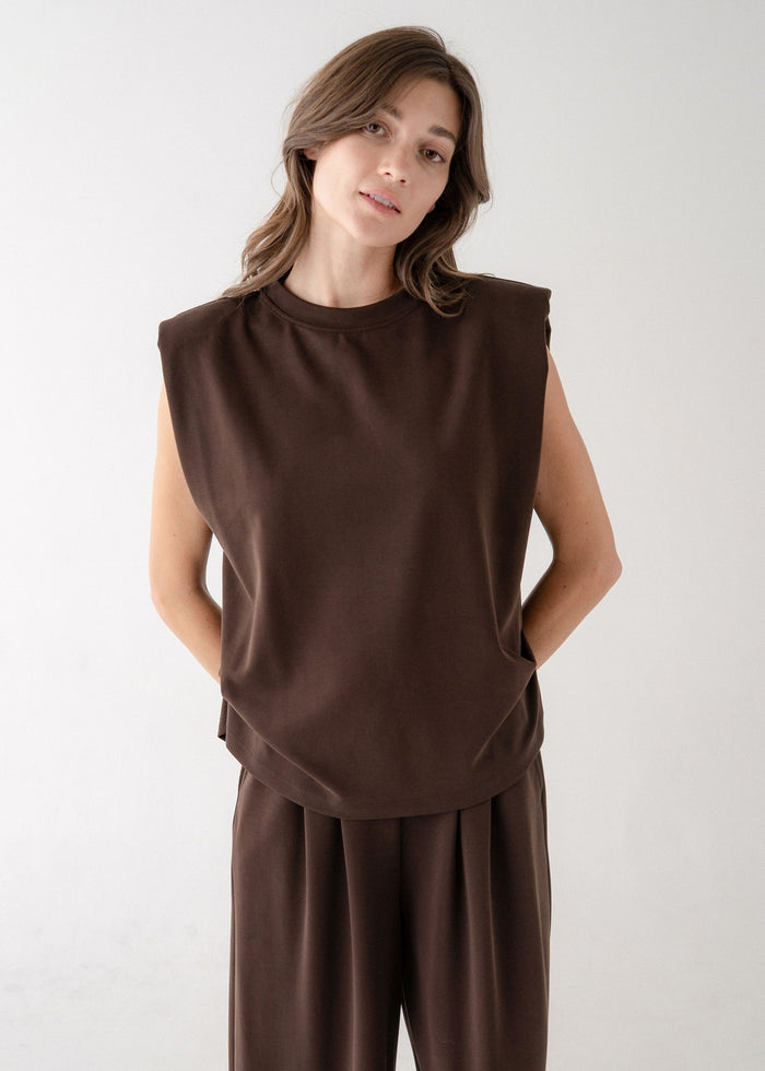 Brown sleeveless top with structured shoulder pads and crew neckline on model.