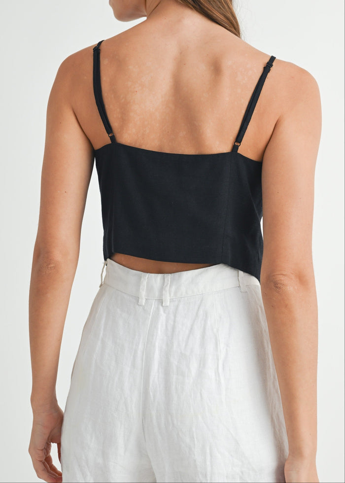 Black crop top with thin spaghetti straps and button-front closure, shown worn with white pants.