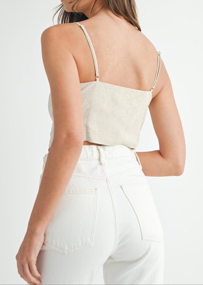 Cream button-down crop top with thin straps, shown from back paired with white denim jeans.