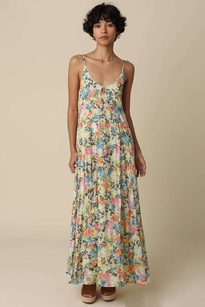 Woman wearing sleeveless maxi dress with multicolored floral print, V-neckline, and thin straps.