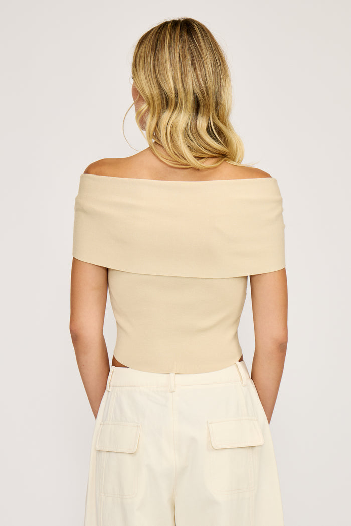 Cream off-shoulder top with short sleeves and folded neckline, shown from back view on model.