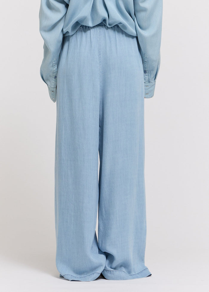 Light blue chambray straight-leg pants with high waist and full-length cut, shown from back view.