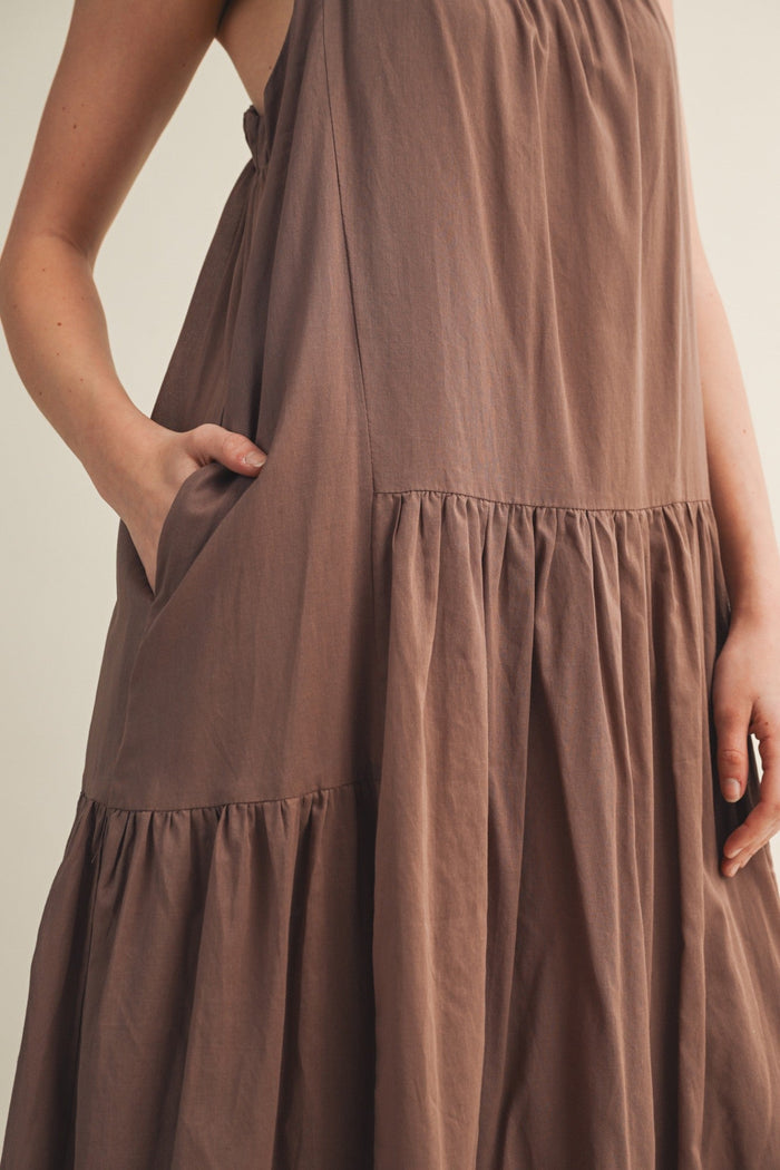 Taupe sleeveless maxi dress with tiered skirt sections and side pockets.