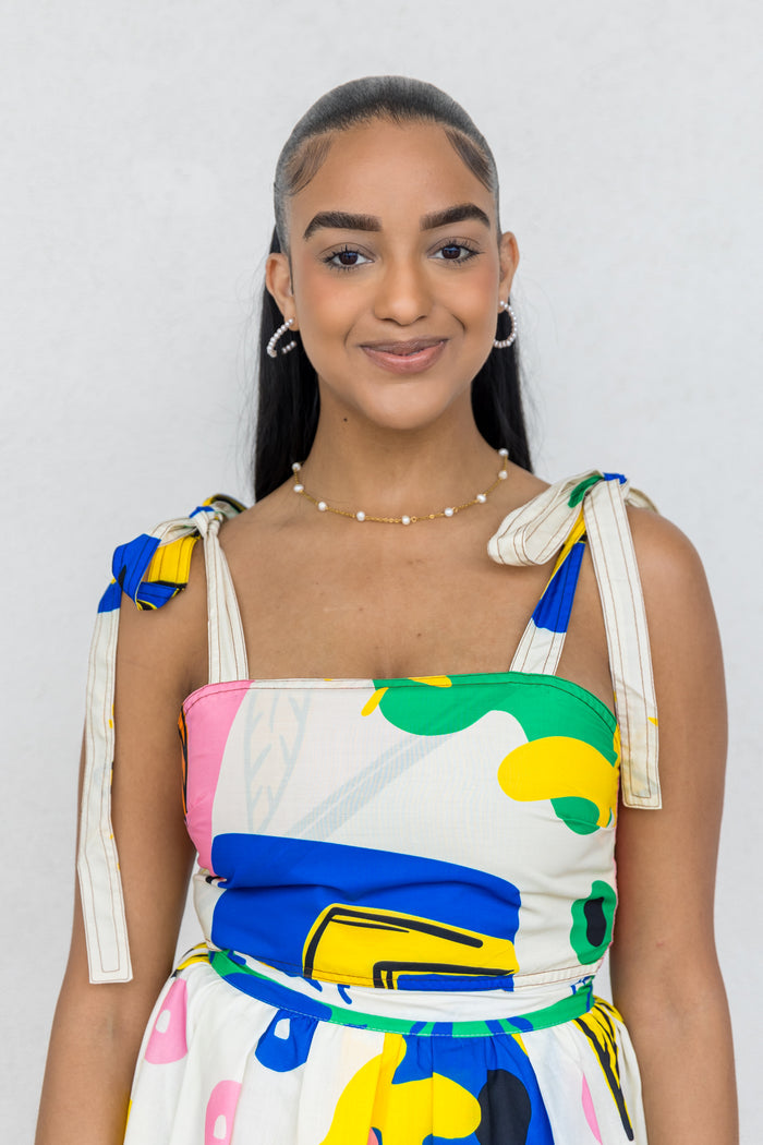 Sleeveless top with colorful abstract print, tie shoulder straps in blue and yellow, and square neckline.