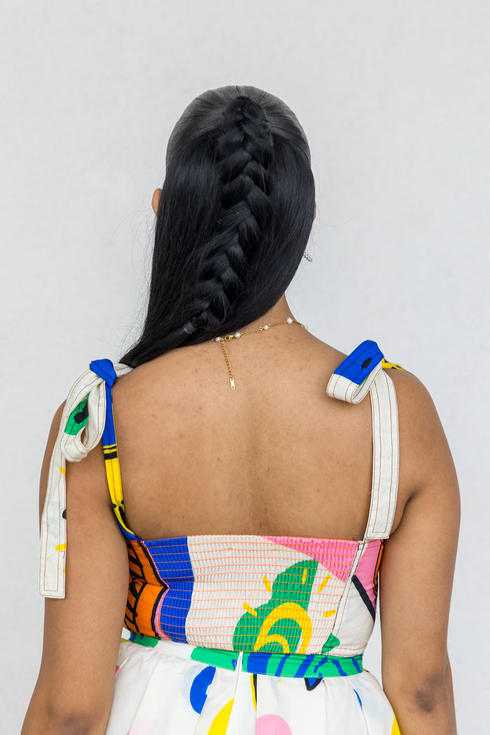 White sleeveless crop top with colorful abstract print, tie shoulder straps, and textured ribbed panel at bust.