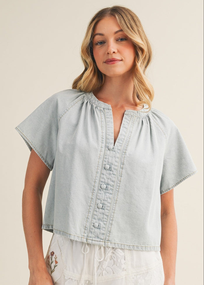 Light-wash denim top with V-neckline, short sleeves, and button-front closure.
