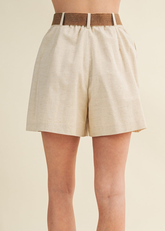 Beige linen pleated shorts with brown textured belt detail at waistband.