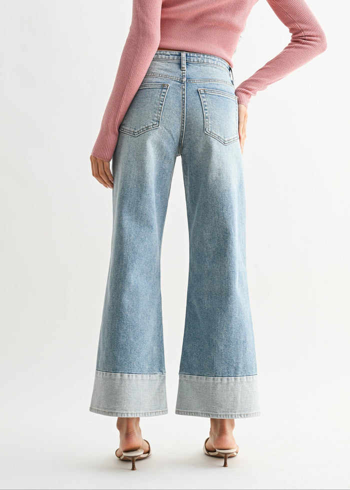Woman wearing a pink sweater and light blue jeans on a white background