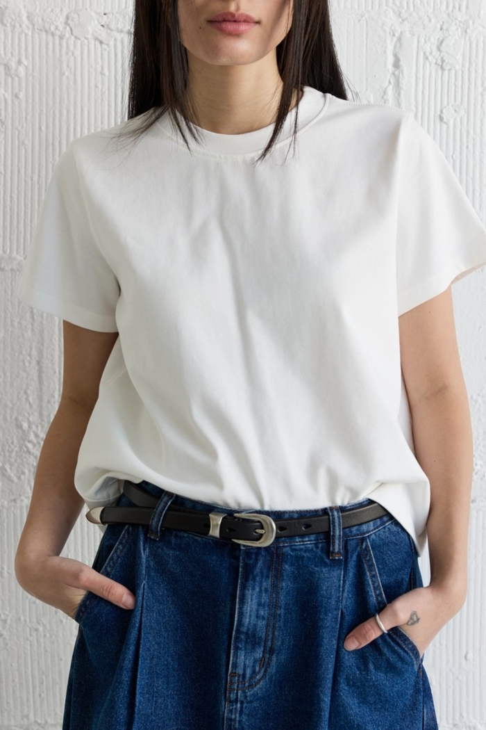 White short-sleeve crew neck t-shirt worn with dark denim jeans and black belt.