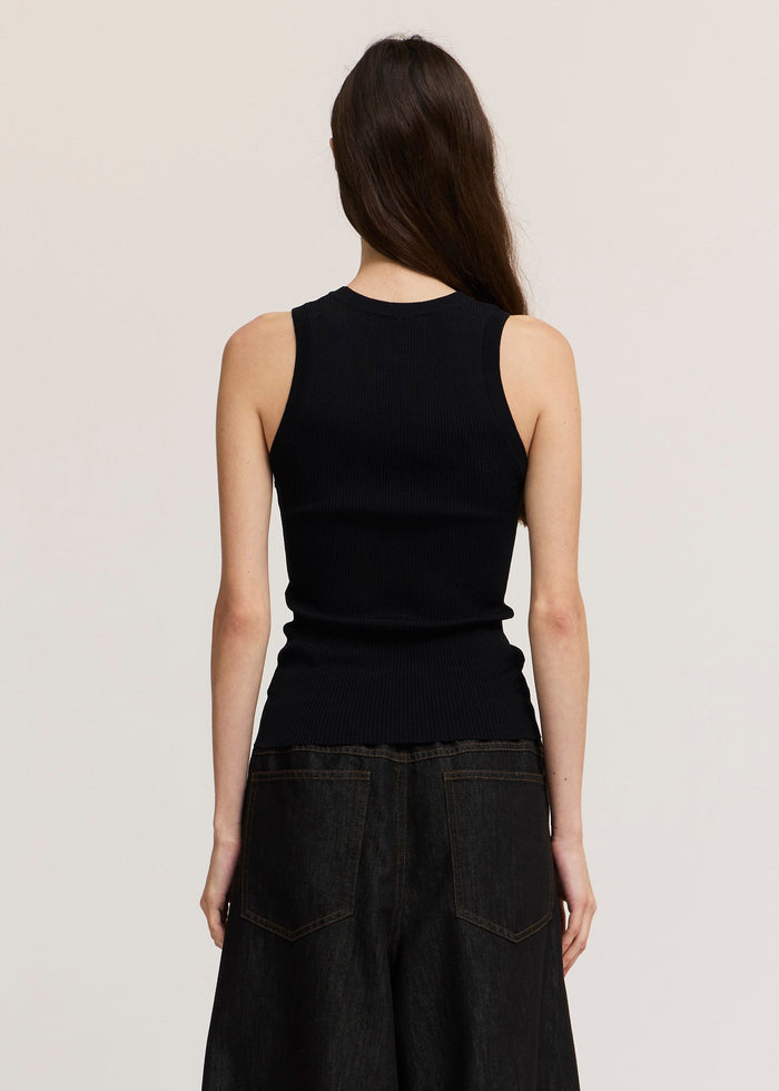 Black ribbed knit sleeveless tank top with crew neckline, worn with dark denim jeans.