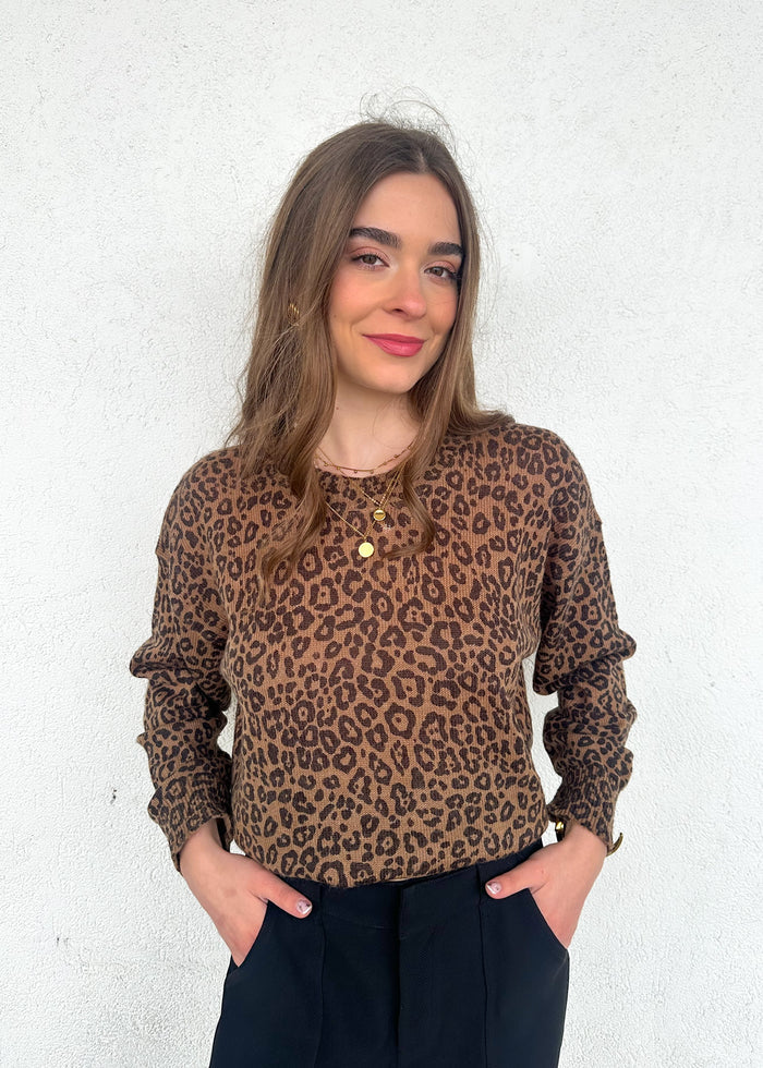 Tan and brown leopard print crewneck sweater with long sleeves worn with black pants.