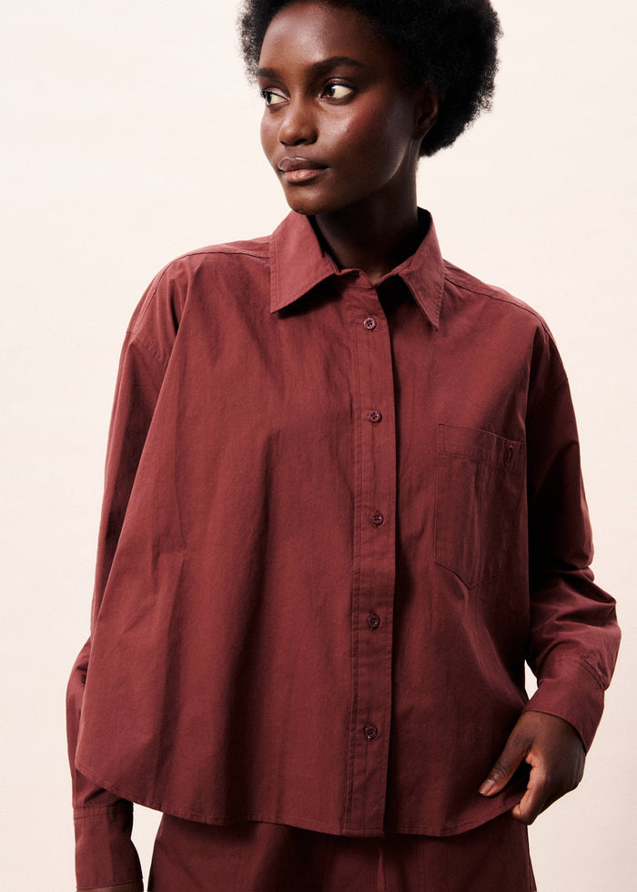 Burgundy button-down shirt with collar and chest pocket, worn unbuttoned over a matching solid top.