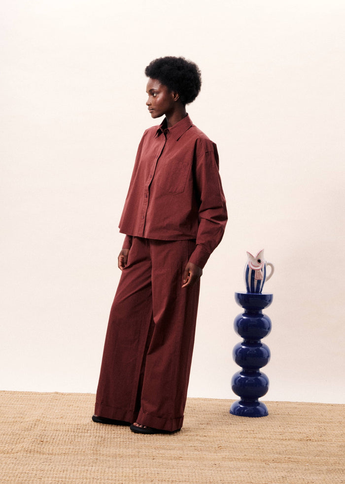 Burgundy button-down shirt with long sleeves worn over matching wide-leg trousers.
