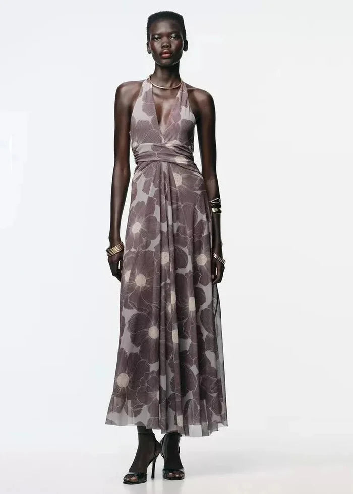 Taupe halter maxi dress with floral print, wrap waist detail, and flowing skirt worn with black ankle boots.