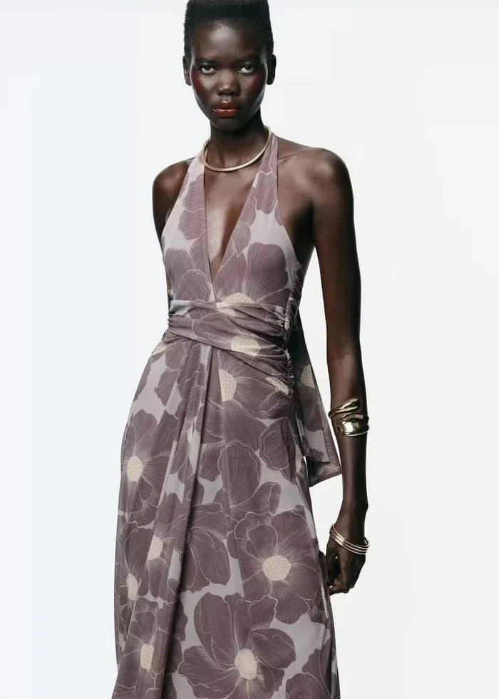 Halter maxi dress in taupe with large floral print, deep V-neckline, and wrapped waist detail.