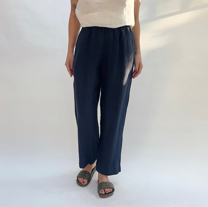 Person wearing navy linen pants on a white background