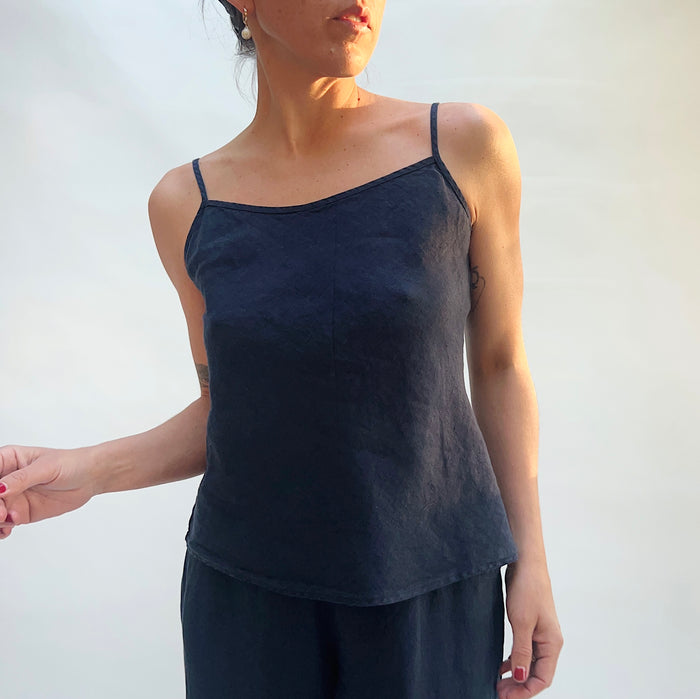 Person wearing a black camisole against a plain background