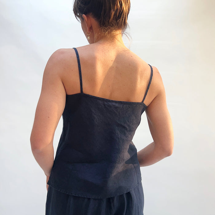 Person wearing a black sleeveless top against a white background, viewed from the back