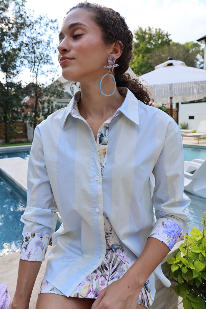 White button-down shirt with rolled sleeves and floral print cuffs, worn with matching floral shorts.