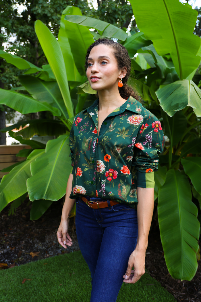 Green button-down shirt with red and pink floral print, short sleeves, worn with dark jeans.