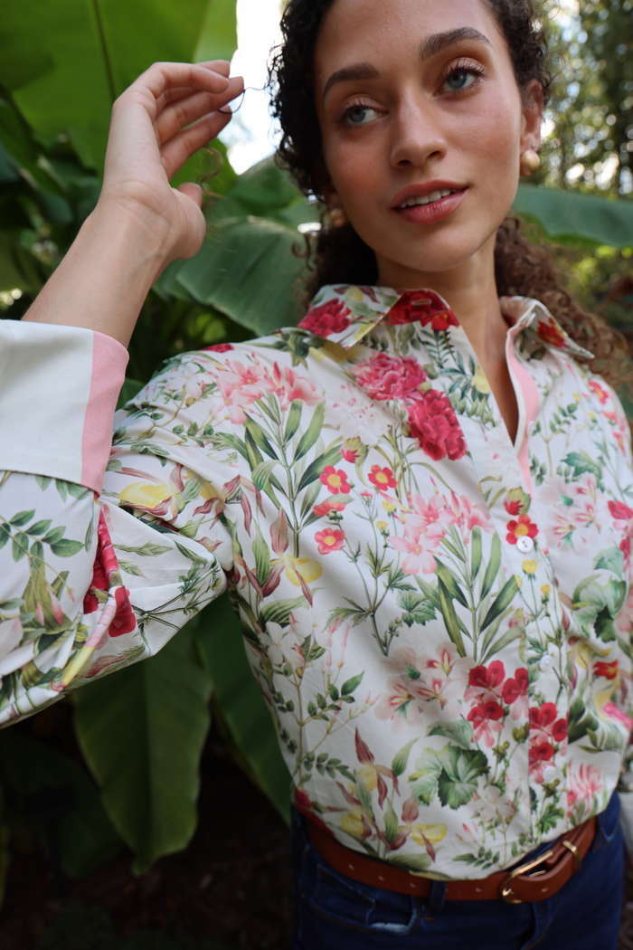 Woman wearing white button-down shirt with red and pink floral print and pink cuffs.