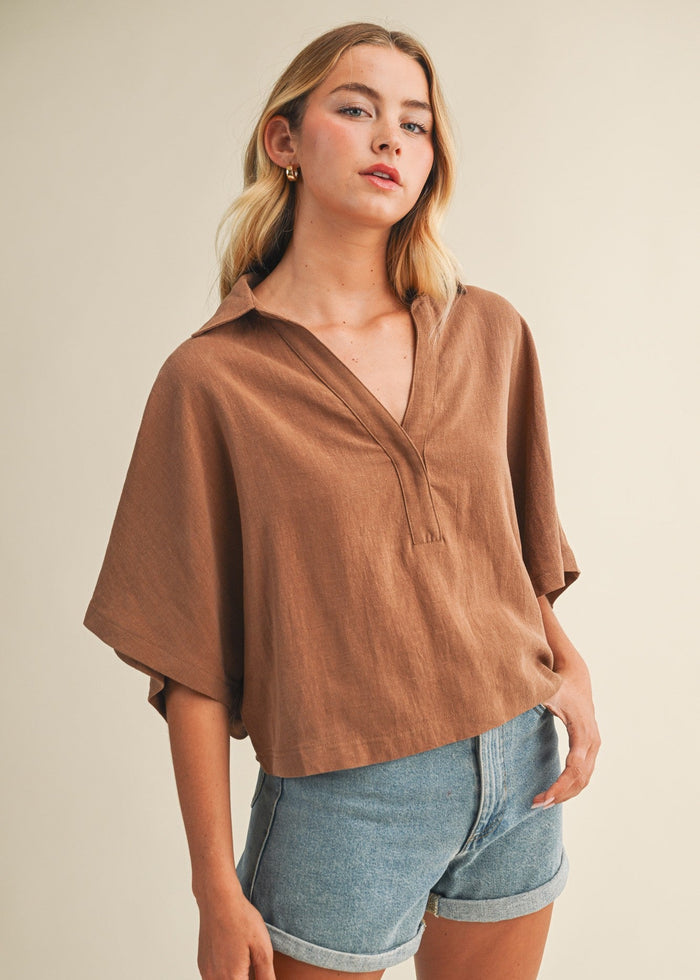 Brown linen popover top with collar and half sleeves worn with blue denim shorts.