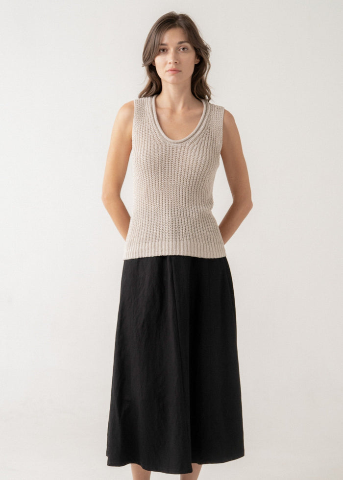 Beige sleeveless ribbed knit tank top with round neckline worn with black midi skirt.