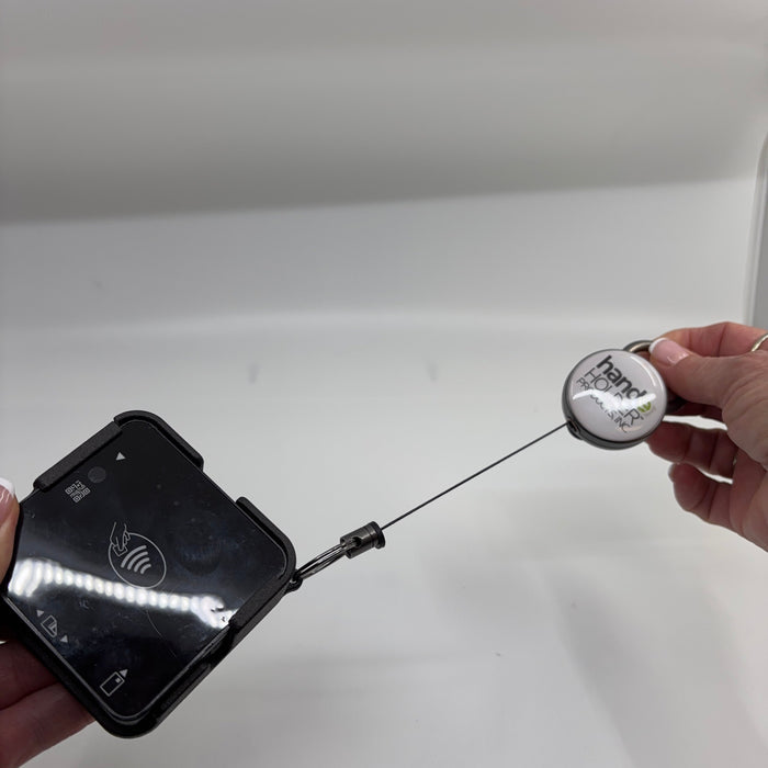 Hand holding a black device with a retractable cable against a white background