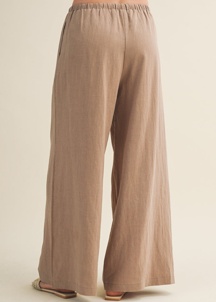 Beige wide-leg pants with elastic waistband shown from back, featuring relaxed fit through hip and thigh.