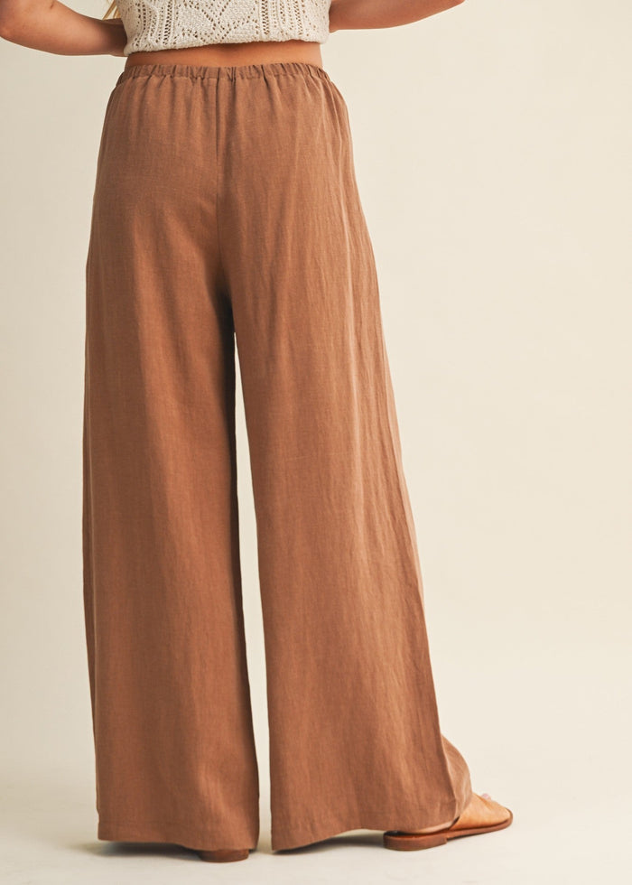 Tan wide-leg pants with elastic waistband worn with cream cable-knit crop top.