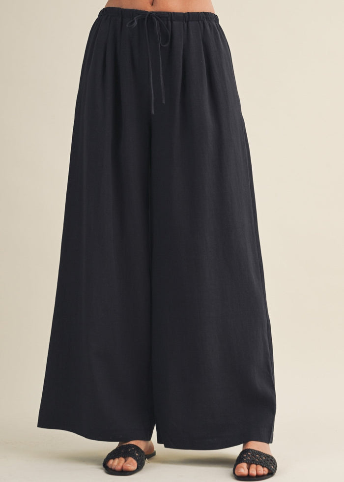 Black wide-leg pants with drawstring waist and full-length cut.