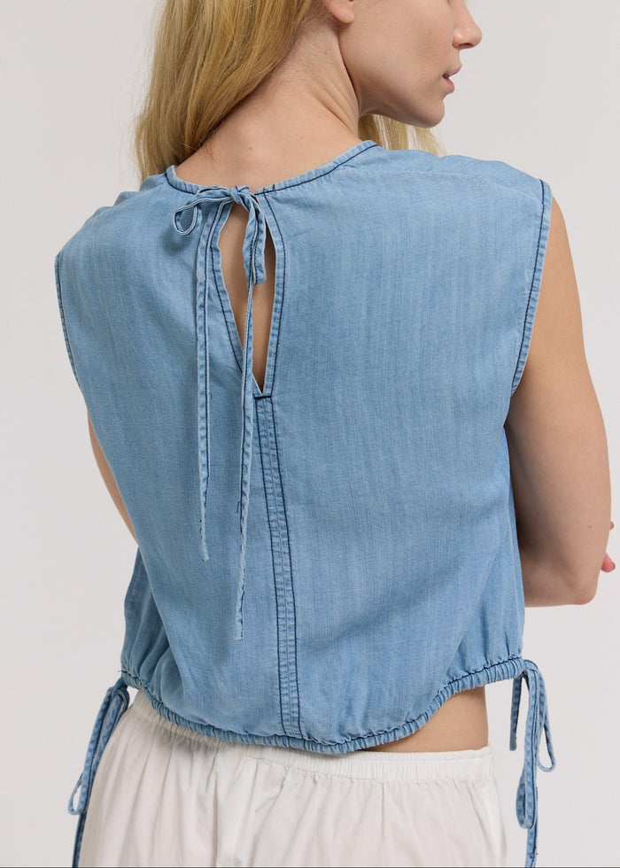 Light blue chambray sleeveless shell top with back tie closure and side drawstring details.