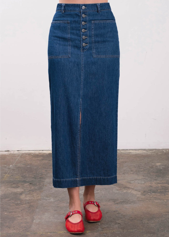 Blue denim midi skirt with button front, patch pockets, and center seam detail.