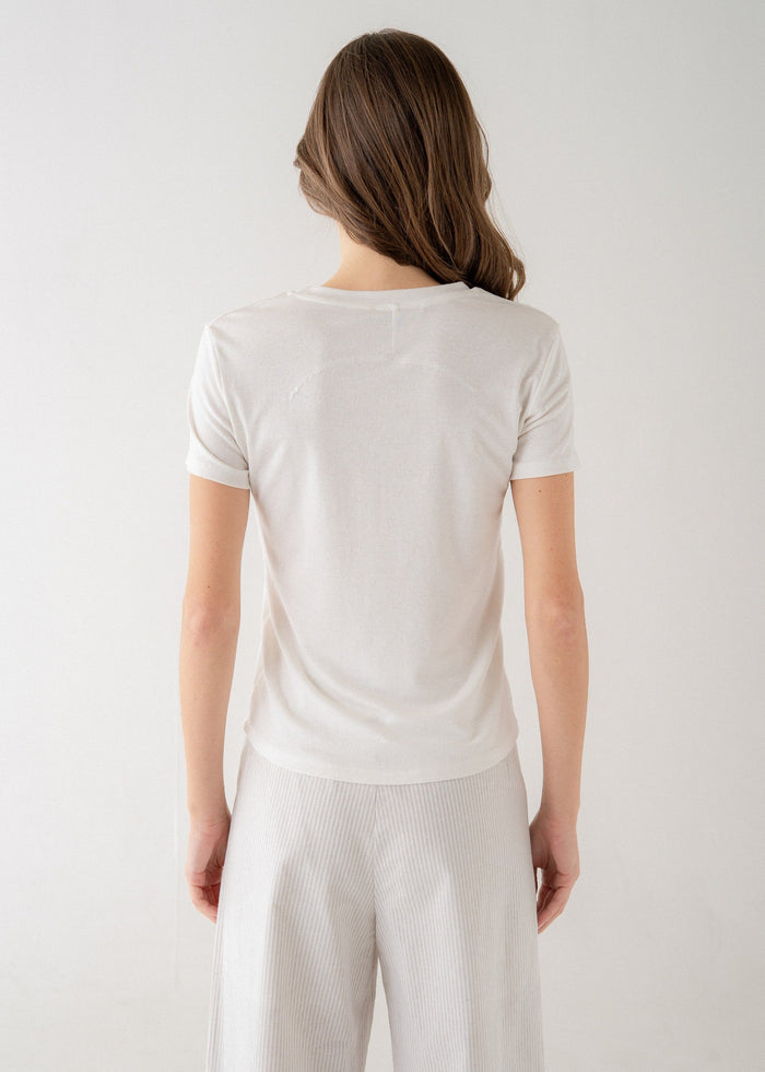 Woman wearing white short-sleeve crew neck tee, shown from back view.