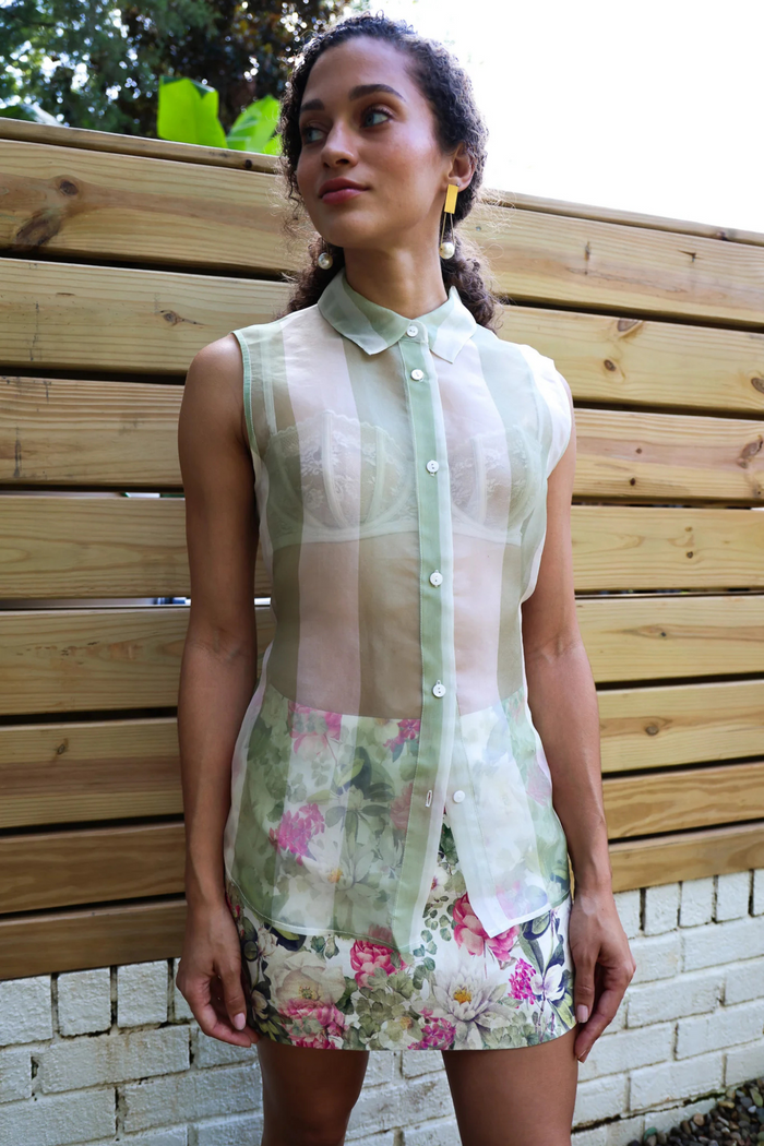 Sleeveless button-down blouse with green and white striped pattern and floral print skirt detail.