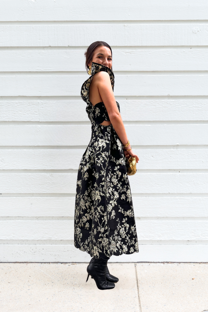 Black midi dress with cream floral print, sleeveless halter neckline, and cutout back detail.