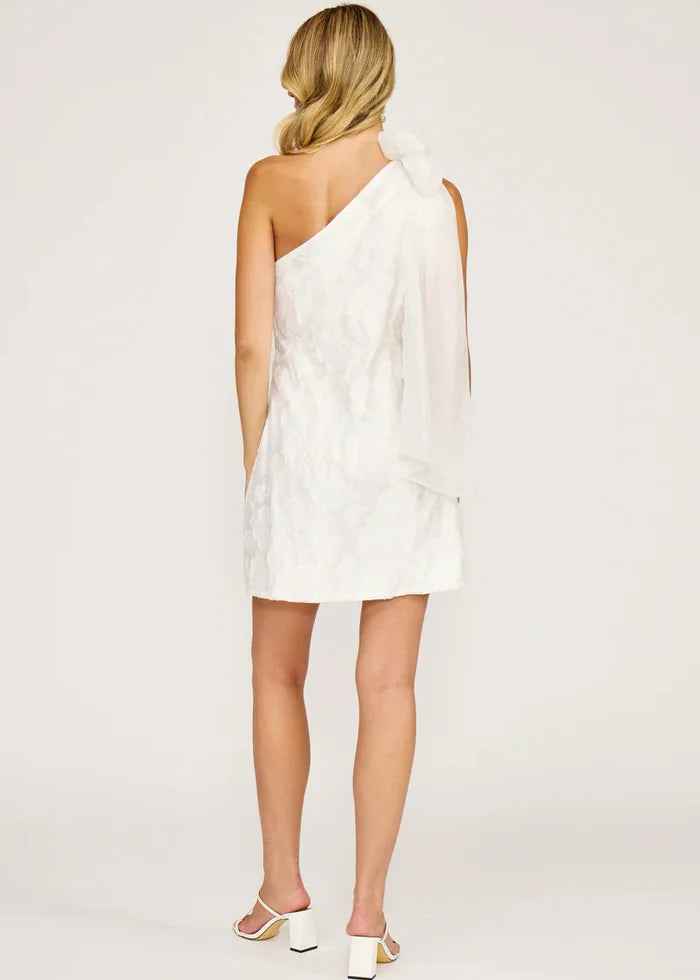 White one-shoulder mini dress with textured fabric and draped shoulder detail, shown from back.