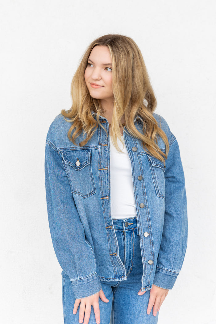 White ribbed knit top worn under a blue denim jacket with jeans.