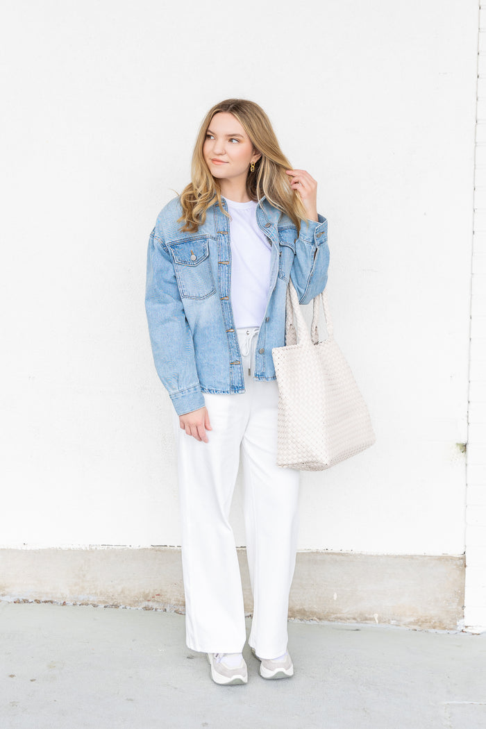 White short-sleeve top worn under a light blue denim jacket with chest pockets.