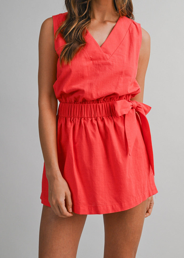 Red sleeveless v-neck romper with gathered waist and side bow tie detail.