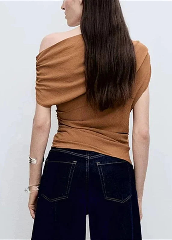 Camel-colored one-shoulder top with ruched fabric detail, shown from back view with dark jeans.