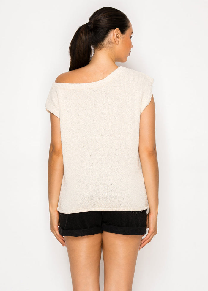Woman wearing cream-colored one-shoulder top with short sleeves and black shorts, shown from back view.