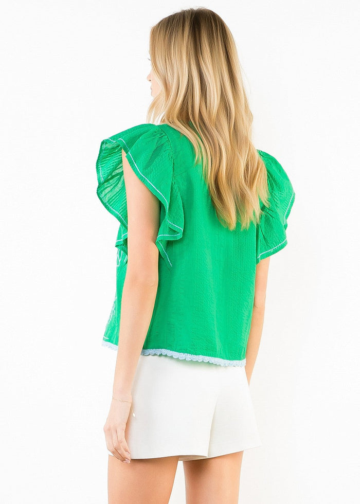 Green short-sleeve top with ruffled cap sleeves and white trim, worn with white shorts.
