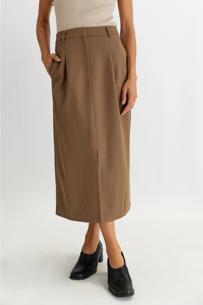 Tan tailored midi skirt with pleated front, side pockets, and center slit hem.