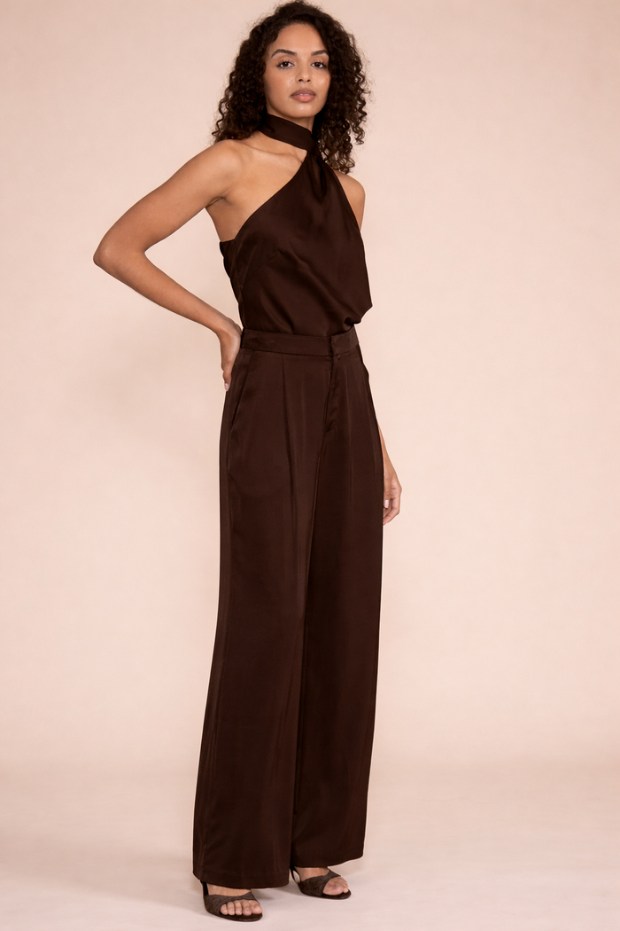 Woman wearing brown satin halter top and wide-leg pants with black slide sandals.
