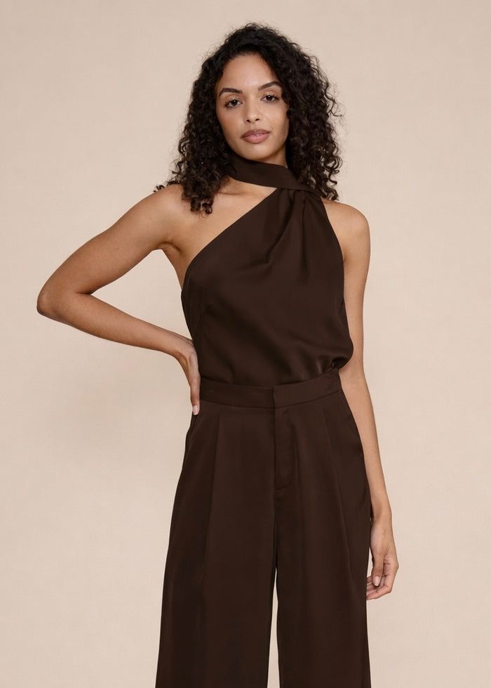 Woman wearing a brown one-shoulder top with matching wide-leg pants against a beige background.