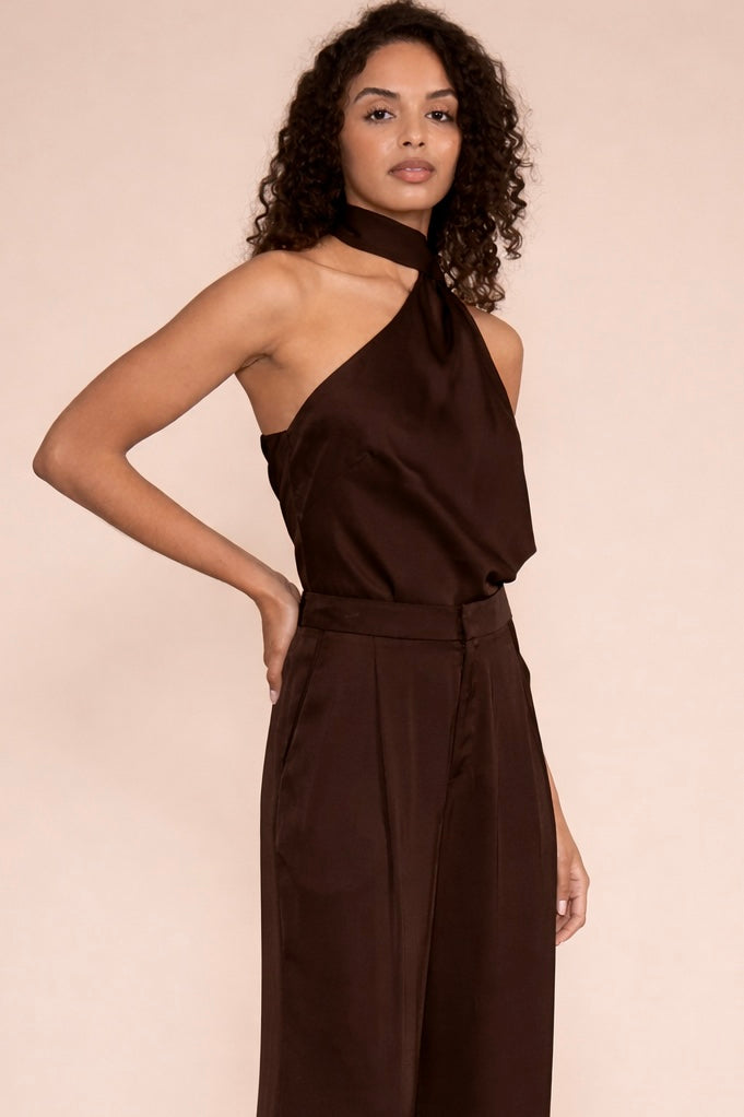 Black one-shoulder halter top with open back worn with matching high-waisted trousers.