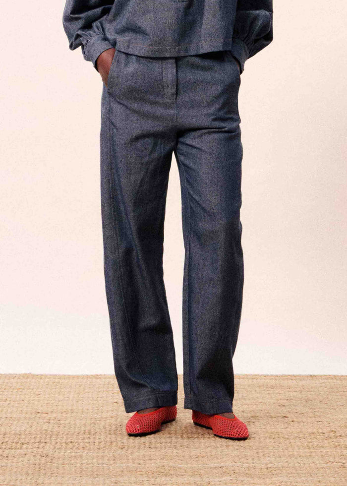 Navy blue jeans with straight legs and front pockets, worn with red knit slippers.