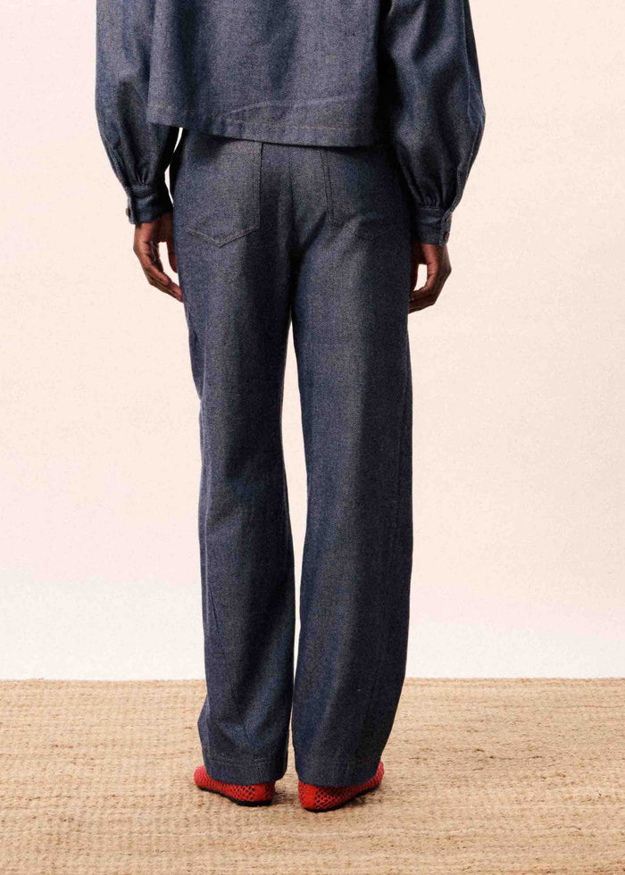 Navy blue jeans with wide legs, back pocket visible, worn with red socks.
